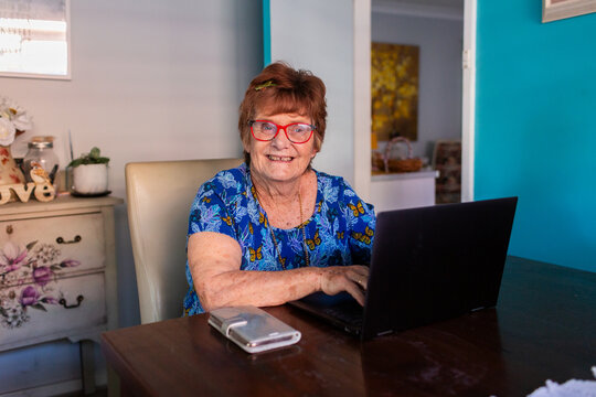 Smiling senior woman using laptop in dining room of house