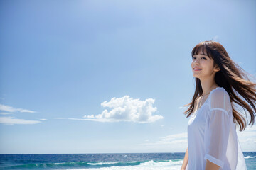 青空をバックに健康的に微笑む若い日本人女性