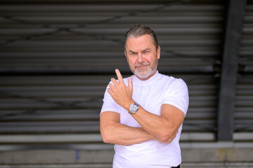 Man with a white t-shirt wearing a fancy watch and looking critically
