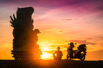 Travel people enjoy beautiful sunset on tropical island Bali near famous architecture landmark 122-meter tall statue Garuda Wisnu Kencana in Bali Indonesia