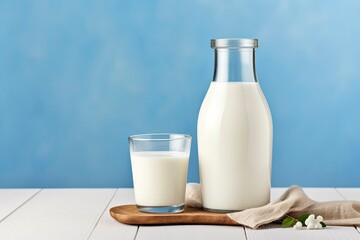 A bottle of milk and a glass of milk on a wooden table on a blue background.