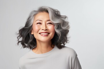 Close-up portrait of a stylish Asian woman in her 50s. Luxurious middle-aged woman with a short gray hair over white background.