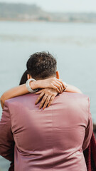 The bride gently hugs the groom in the park, wrapping her arms around his neck, close-up
