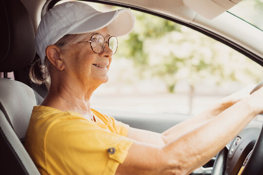 Close up portrait of senior looking woman with glad positive expression, being satisfied with unforgettable journey by car, sits on driver`s seat, enjoys music. People, driving, transport concept