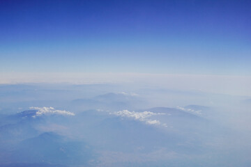 peaks from high mountains with clouds and dense fog during a flight