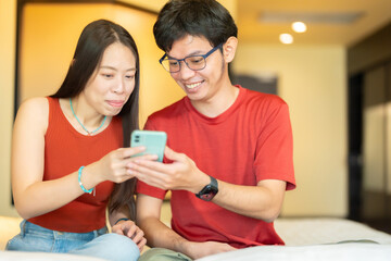 Close-up photo of Asian business man and woman Look at the smartphone together Smile and work related to the industry with the company's online marketing and customer product orders. in the hotel room