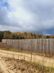a fence behind which you can see an autumn park with bright leaves