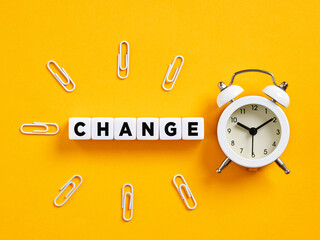 The word change on cubes with alarm clock and paper clips. Time for change.