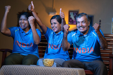 excited family celebrating victory of Cricket Team in Indian jersey, watching on tv or television...