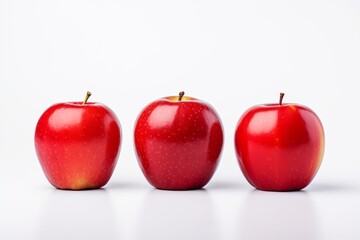 Photo of three red apples standing in a row on a white minimalistic background. Fresh, appetizing, tasty and healthy fruits.