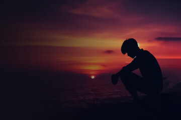 Fototapeta premium Silhouette of a person crouching against a sunset sky