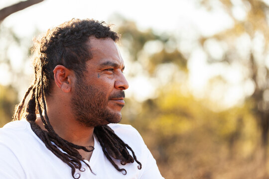 Side profile of Aboriginal Australian man looking off into bushland