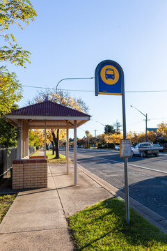 Bus stop sign and shelter on street of rural country town - public transport