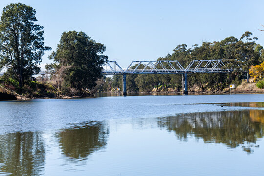 Morpeth bridge seen from along river on sunlit day