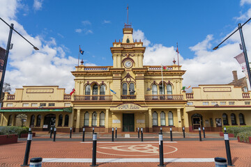 A grand historic Town Hall with a clock tower behind rows of bollards around road partition
