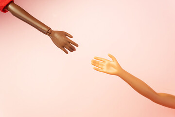 Two doll hands reach for each other on pink background. Different skin tones and races. Stop...