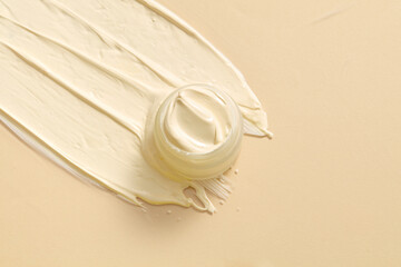 Flat lay of a unmarked jar streaks of cream with an pastel color texture are brushed against a...
