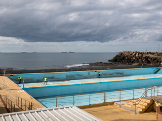 Empty seaside olympic sized swimming pool being cleaned