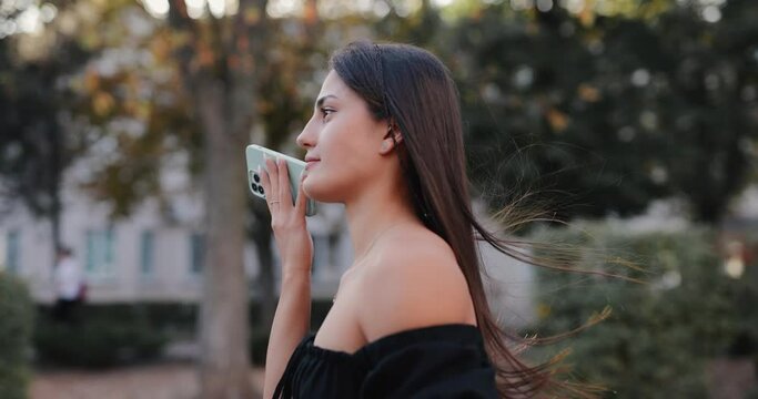 Slow motion smiling woman listens to a voice message at the autumn city alley