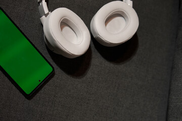 detail of large headphones next to cell phone on the sofa
