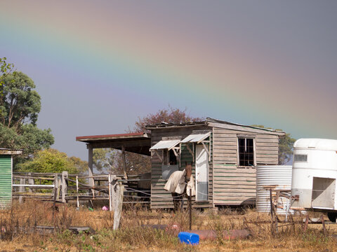Dilapidated building with horses, rainbow and stormy sky