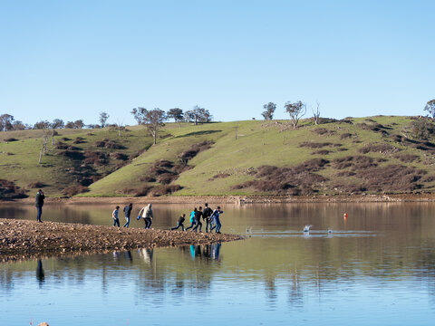 A group of people skimming stones over the water of a storage dam