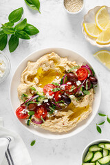 Greek style vegan mediterranean hummus with fresh vegetables, olives, olive oil and feta cheese. Top view