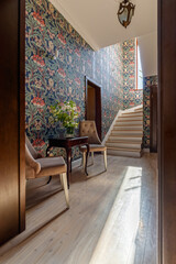 A coffee table with a bouquet and a cup, standing near the stairs to the second floor