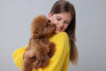 Little child with cute puppy on light grey background. Lovely pet