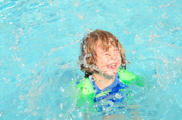 Fototapeta na wymiar Cute boy learning to swim in the pool. Splashes, emotions, swimsuit. Family holiday at the resort, children on a trip. Summer holidays