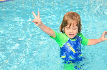 Fototapeta na wymiar Cute boy learning to swim in the pool. Splashes, emotions, swimsuit. Family holiday at the resort, children on a trip. Summer holidays
