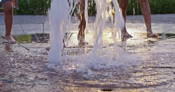 Feet of people walking on a fountain in the park on a summer day