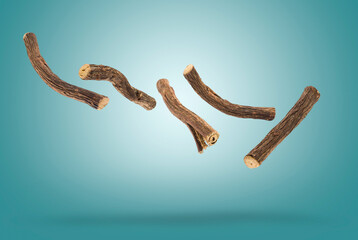 Sticks of liquorice root floating on blue background.