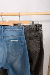 Two pairs of jeans hanging on a wooden clothing rack