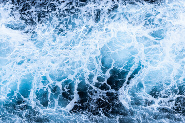 High angle view of a blue abstract background with sea foam design. Drone pointing view