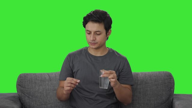 Sick Indian man taking medicine Green screen