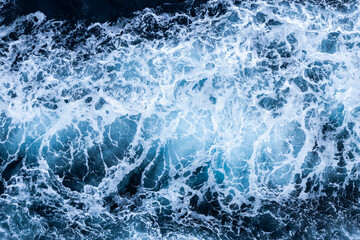 Fototapeta premium High angle view of a blue abstract background with sea foam design. Drone pointing view