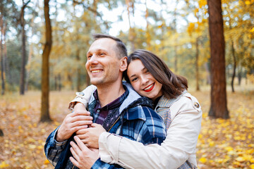 Young Cute Female Hugs Boyfriend. In Autumn Outdoor. Lovers Walking in Park. Attractive Funny Couple. Lovestory in Forest. Man and Woman. Cute Lovers in the Park. Family Concept. Happy Couple.