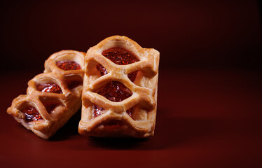 Puff pastry pastry with lingonberry jam on a dark red background. Cookies with lingonberry jam.