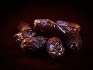 Several ripe dates on a dark red background. Delicious dates on red.