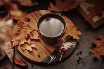 Cozy scene for cold weather with cup of coffee and dried leaves. Autumn composition with hot drink...