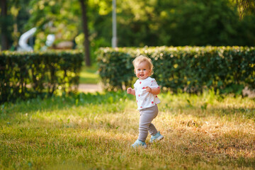 Caucasian little child baby in the park in summer in the setting sun, outdoor walking