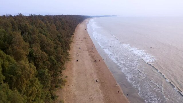 A tranquil Nargol sunset paints the sky in warm hues as tree silhouettes embrace the horizon. Beech leaves whisper in the breeze, harmonizing with gentle waves' rhythmic lullaby. Gujrat India Beach