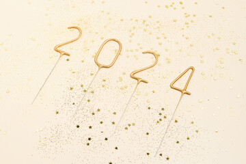 Golden numbers 2024 in the form of sparklers side view and gold glitter stars on beige isolated background. New Year and Christmas celebration concept, wishes and congratulations, idea for a postcard