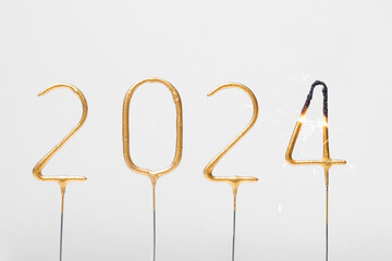 burning golden numbers 2024 sparklers on gray isolated background. the concept of celebrating the...