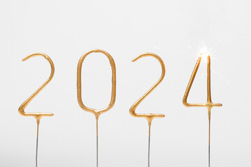 golden numbers 2024 and burning sparkler number 4 on gray isolated background. The concept of celebrating the new year, ending the old one, greetings and wishes
