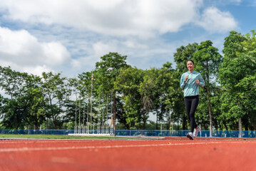 Young Asian women are exercising with outdoor running with a running track background in the morning. Concept healthy running and outdoor exercise,Tracking shot,