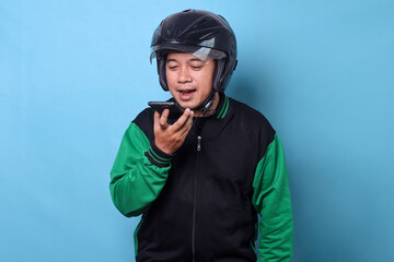 Online motorcycle taxi driver in helmet talking with customer in the loud-speaker mode of smartphone