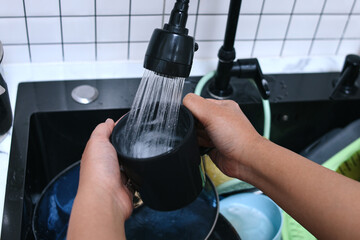 Close-up of hands cleanse a mug at kitchen sink