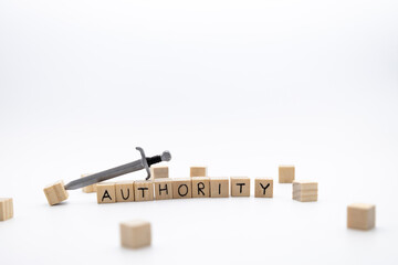 The wooden cubes with the word AUTHORITY and the weapon around against white background.